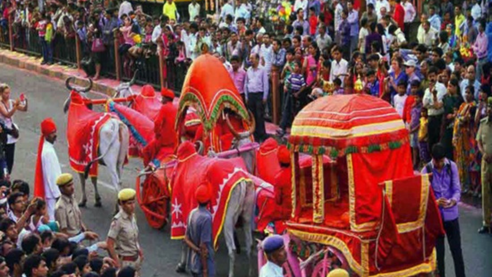 Women in vibrant traditional Rajasthani ghagra-choli carrying decorated Gangaur idols in the grand procession